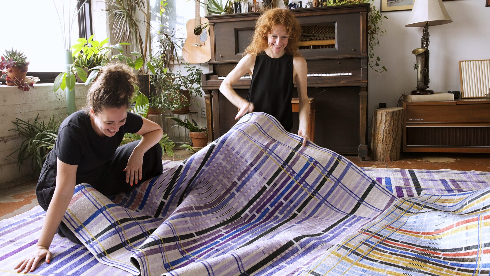 Giorgia Lupi and a collaborator unroll the Unraveling Stories rug in the studio.